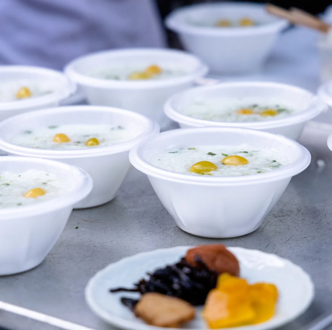 白い使い捨て容器に盛られた温かいお粥が並ぶ。銀杏粥神事の様子